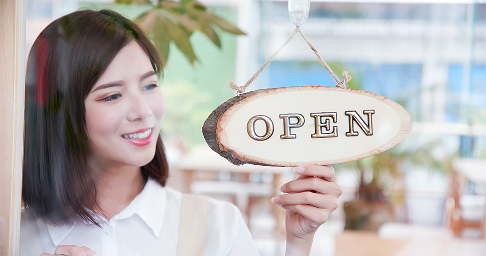 woman daydreaming about flipping over a sign on her new shop