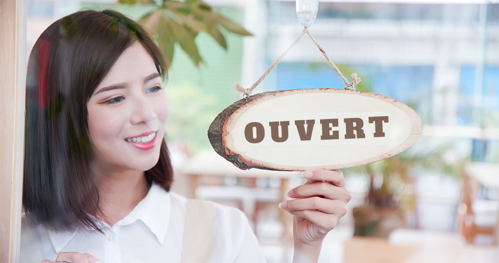 femme qui rêve de retourner une pancarte indiquant l’ouverture de son nouveau magasin