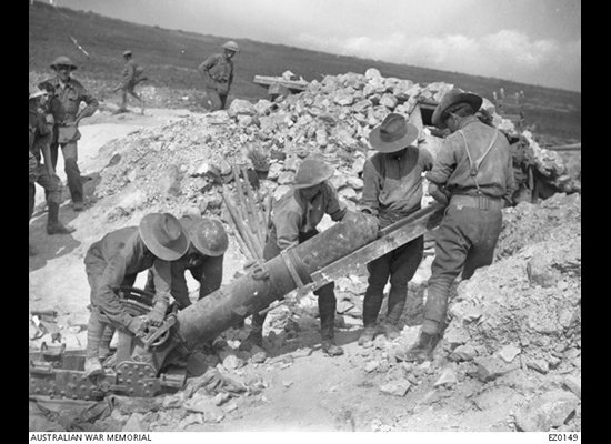 Soldiers load a large, six foot long gun that is planted in the trench and aimed at about a 30 degree angle.