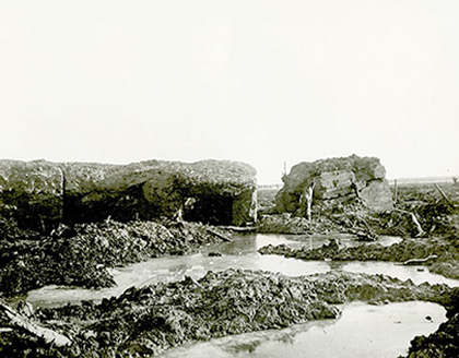 The remains of German blockhouses after war; tall, rock masses are used for defence, behind which is muddy terrain with many puddles