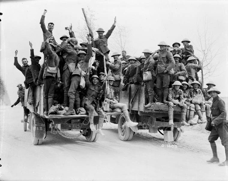 Soldiers laying in the trenches looking across a field into a city centre