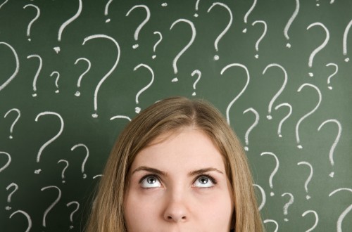 Woman thinking with question marks around her head.