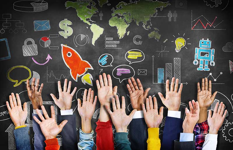 Group of diverse hands raised in front of a chalkboard with symbols