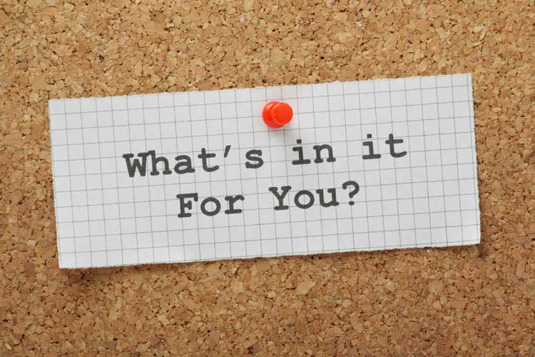 A note pinned on a cork board that says 'What's in it For You?'