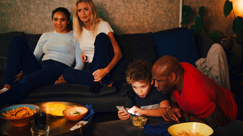 Family watching TV with a child and parent on the phone