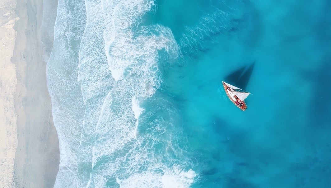 Vue du haut, un bateau dans l’eau resplendissante à la plage 