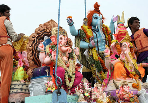 Hindu devotees use crane to lift Lord Ganesha idol for immersion during festival.