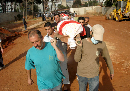 Funeral procession for civilians killed in Beirut. Men are carrying the deceased on wooden stretchers placed on their shoulders. The corpses are wrapped in fabric.