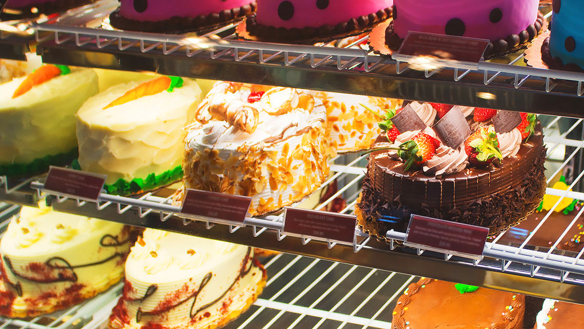 birthday cakes being sold in a glass display case.