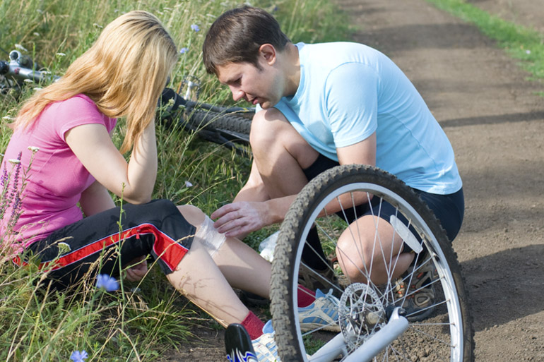 Young man helping a girl who has fallen off her bike