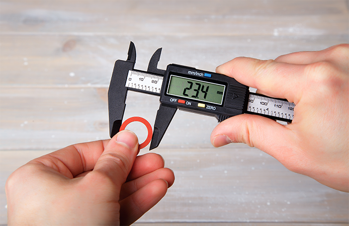 Caliper measuring the width of a red metal ring.png