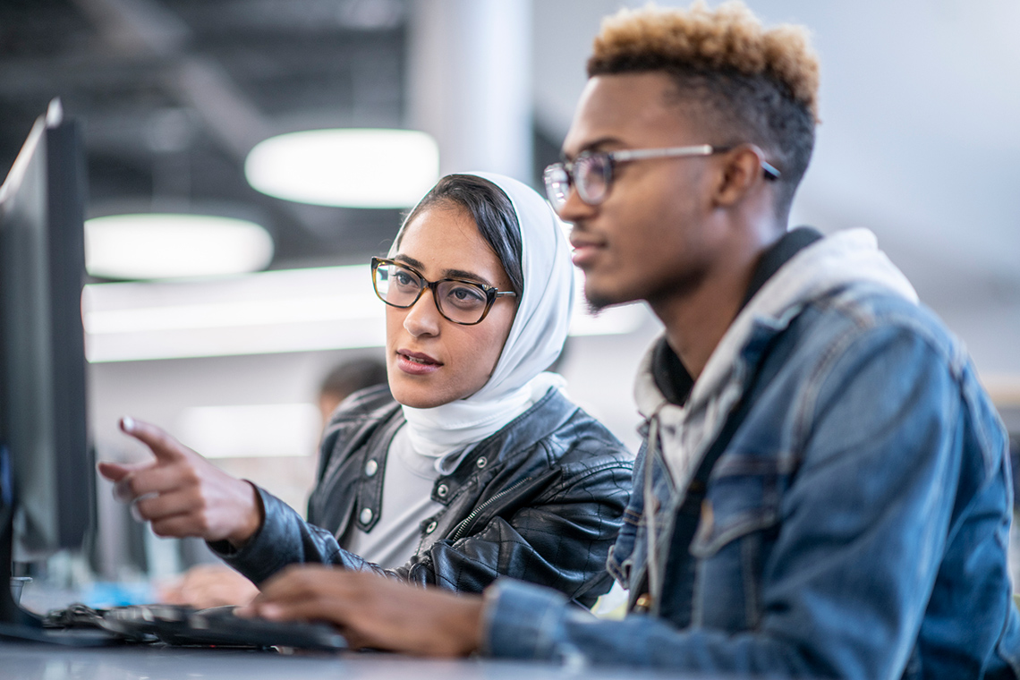 Two people work at a computer together