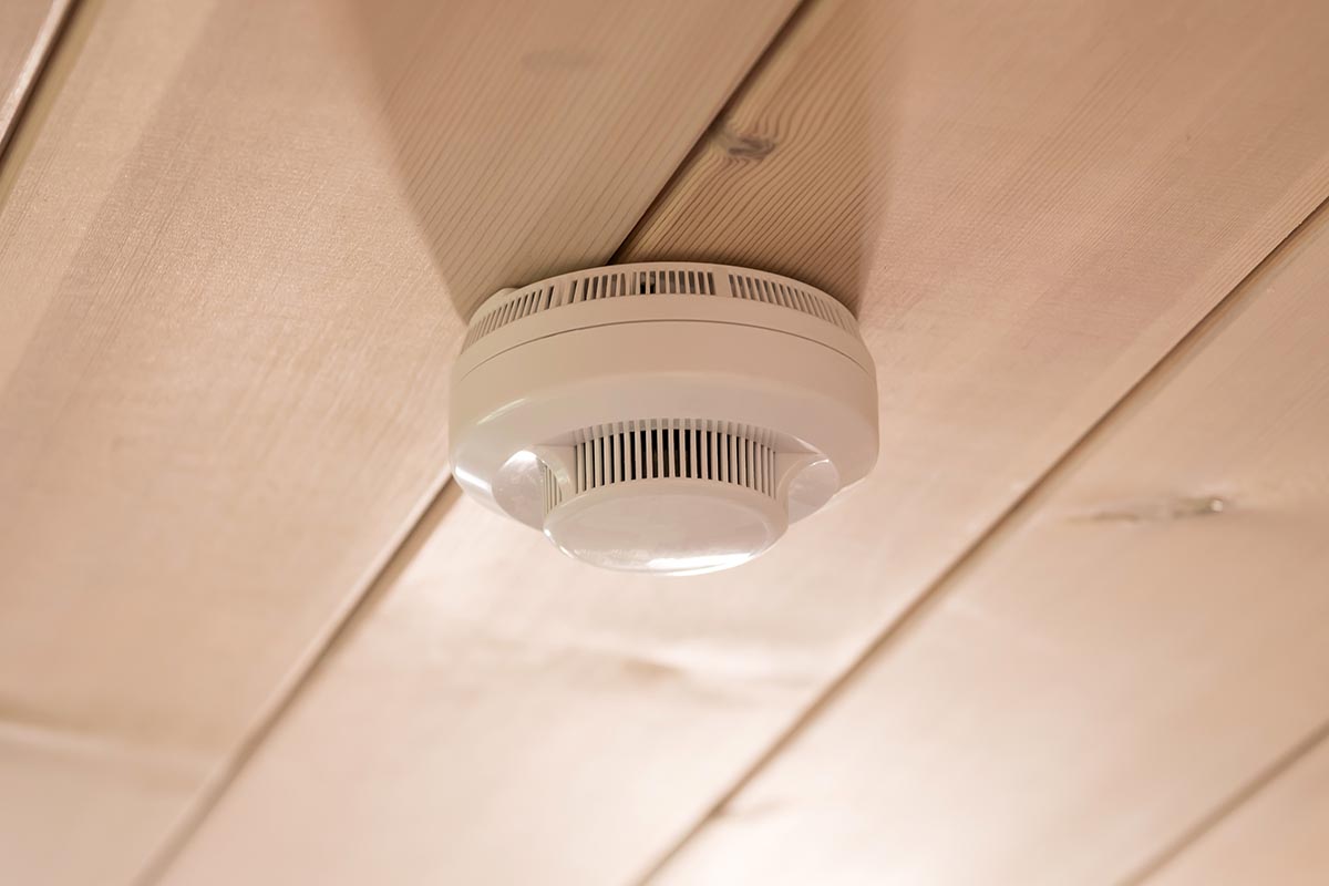 Smoke and carbon monoxide detector in a wooden house on the ceiling