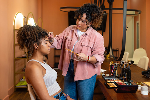 A makeup artist works on a client’s face.