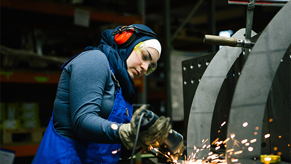 A metal manufacturing worker using a grinder