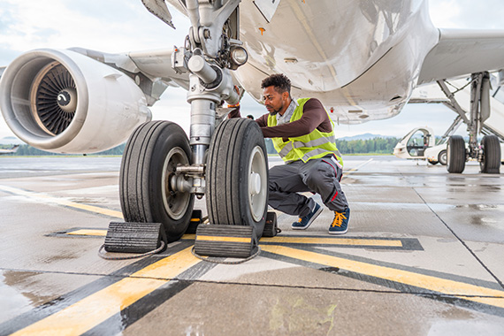 An airplane mechanic working on a plane’s wheels. 