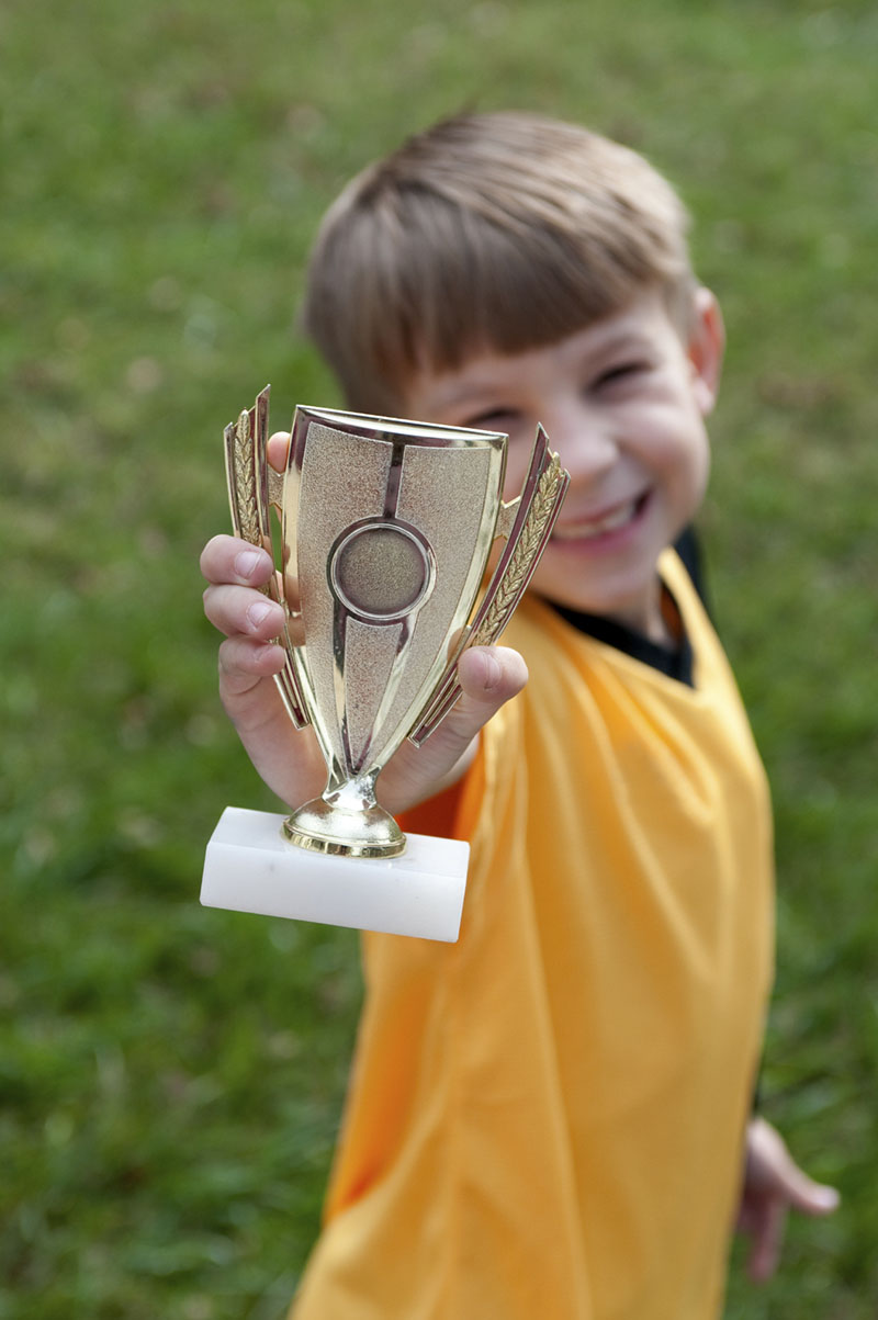 Boy proudly holding his sports trophy